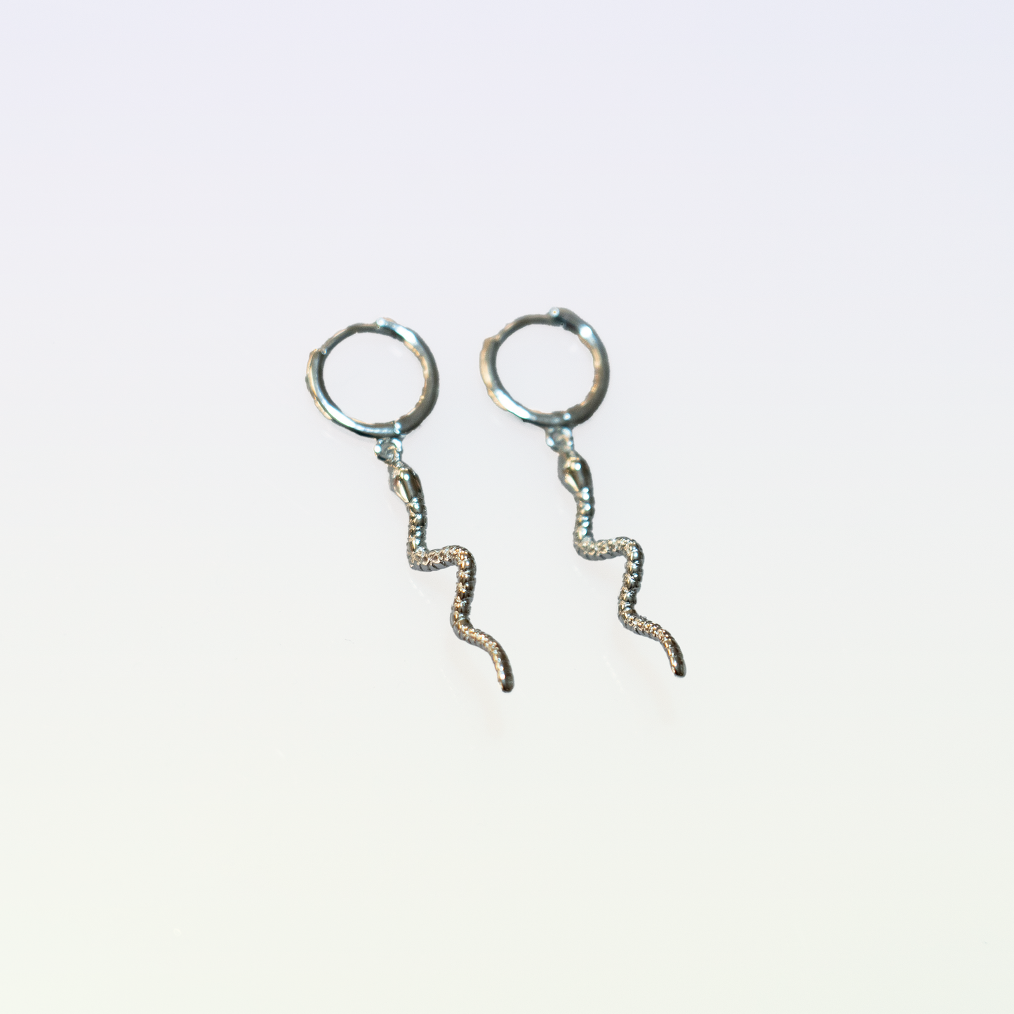 These sterling silver earrings feature a unique snake-shaped design. The earrings have a closed loop closure, allowing for secure and comfortable wear. The intricate, winding shape creates an eye-catching and distinctive accessory.