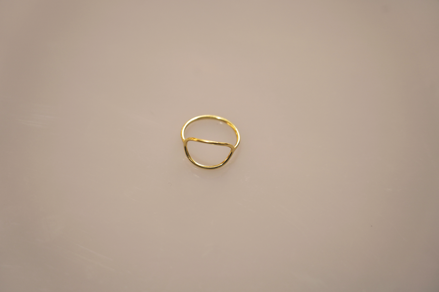 A simple, elegant gold vermeil ring forming a perfect circle, with a smooth, polished surface reflecting light softly. The slender band appears delicate yet sturdy, a timeless accessory suitable for any occasion.