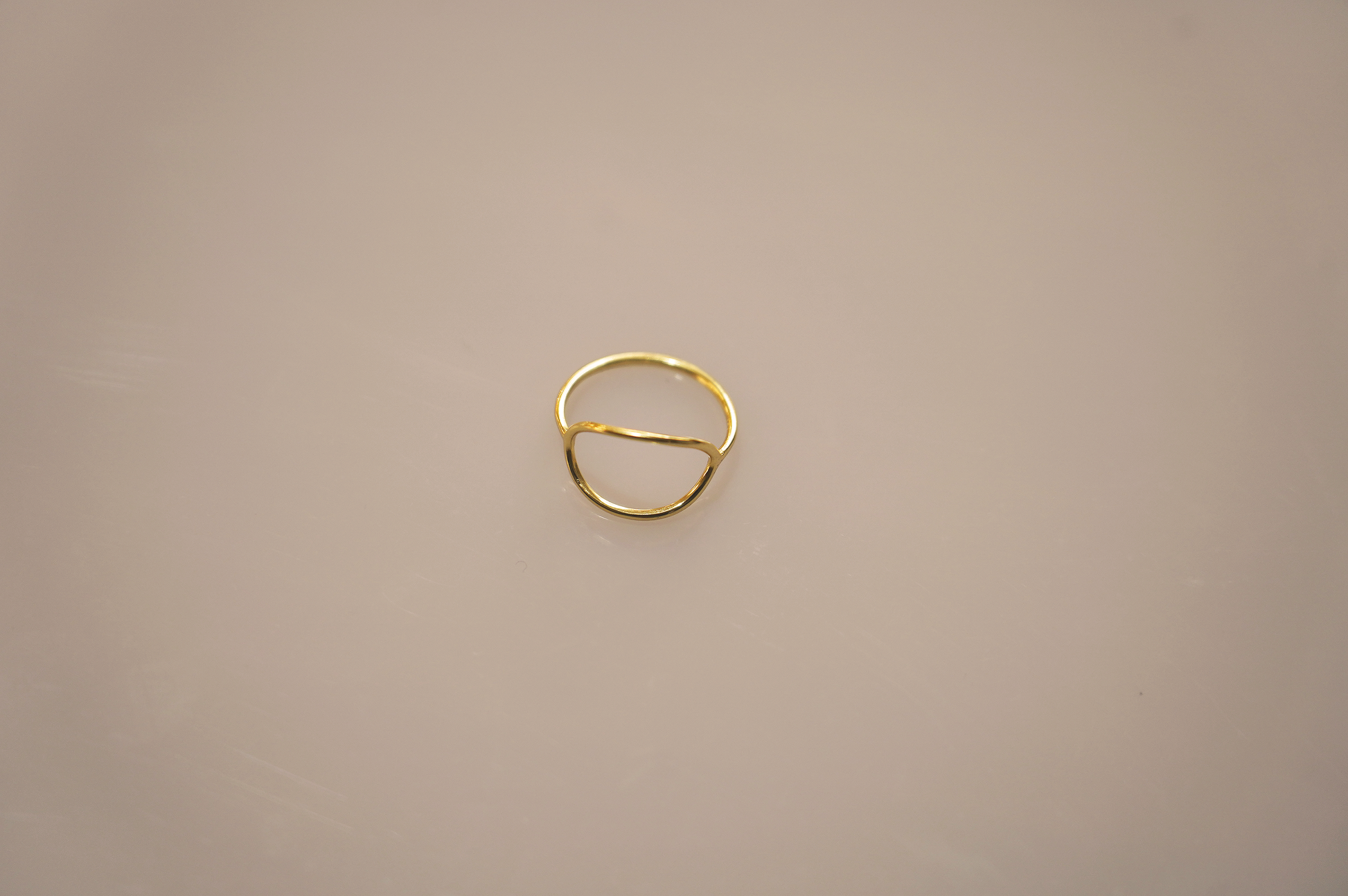 A simple, elegant gold vermeil ring forming a perfect circle, with a smooth, polished surface reflecting light softly. The slender band appears delicate yet sturdy, a timeless accessory suitable for any occasion.