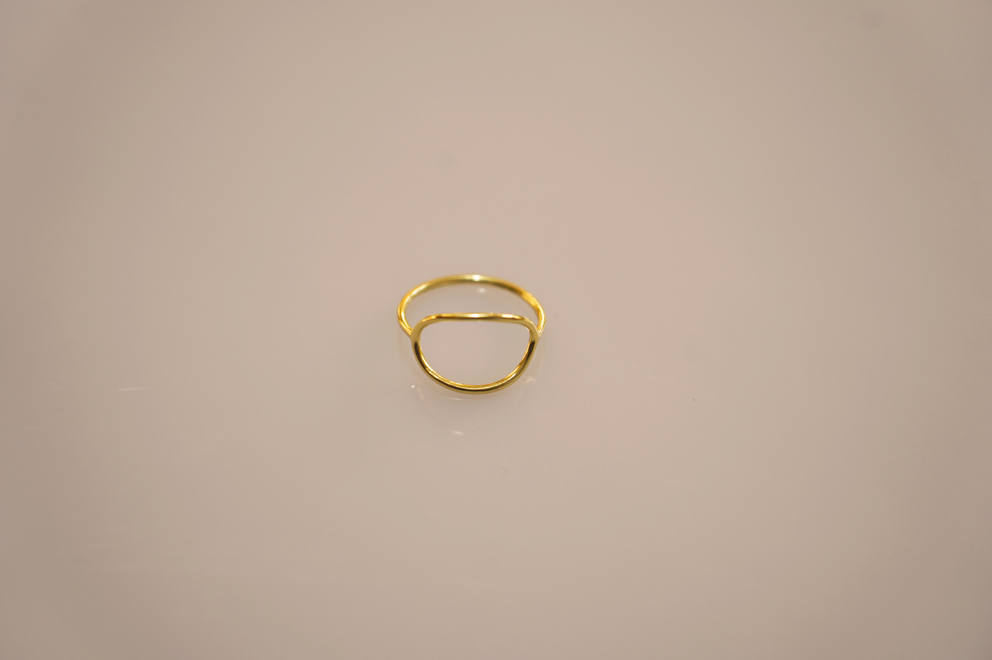 A simple, elegant gold vermeil ring forming a perfect circle, with a smooth, polished surface reflecting light softly. The slender band appears delicate yet sturdy, a timeless accessory suitable for any occasion.