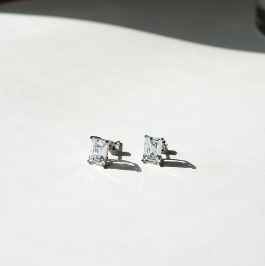 These stud earrings showcase brilliant emerald-cut cubic zirconia stones set in polished sterling silver. The secure push-back closure complements the minimalist design, while the emerald cut enhances the stone's natural sparkle and clarity.