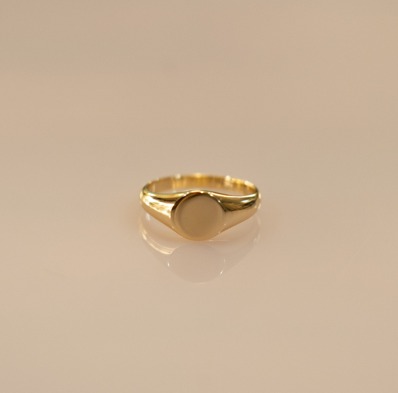 The ring forms a simple, circular shape that elegantly wraps around the finger. The sterling silver band is coated in a warm, golden layer of vermeil, giving it a timeless look reminiscent of classic Roman medallion designs.