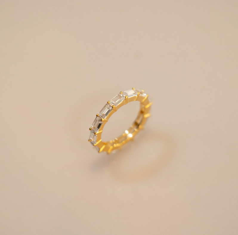 The image shows a ring featuring a row of rectangular-shaped diamonds or diamond-like stones set in a band of gold vermeil. The setting appears to be a prong setting, securely holding the stones in place.