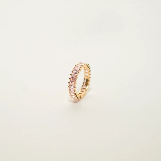 A gold-toned ring made of silver with 18k gold vermeil. It features a row of sparkling, colorless baguette-cut cubic zirconia stones along the top. The band is polished and shiny. The design is modern and minimalist.