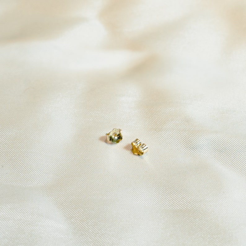 Gold ball stud earrings on thin post. Polished round beads, post and butterfly closure. 2mm diameter. Solid 14K gold, no plating or gemstones. Minimalist style.