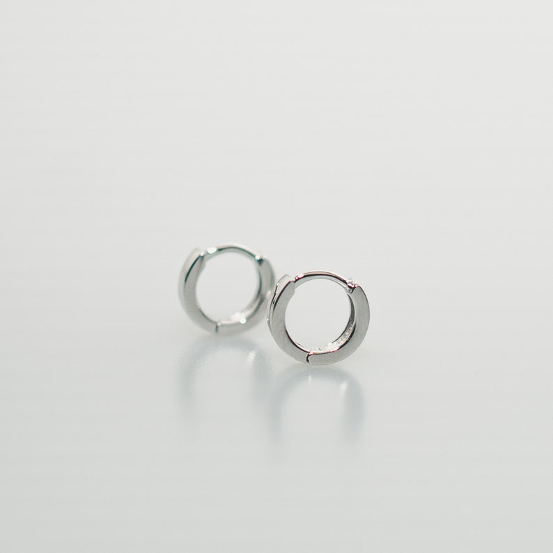 Round hoop earrings in sterling silver, 10mm diameter, 1-3mm thick. Hinged closure for secure fit. Smooth, polished finish. Lightweight and comfortable for cartilage, daith, rook or helix piercings.