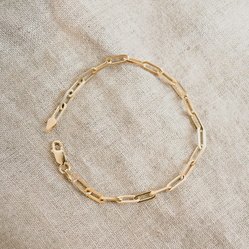 Delicate gold-toned bracelet with an interlinking chain-like pattern. The bracelet has a simple clasp closure, allowing for easy wear and removal. Made of a combination of sterling silver and a gold plating, creating a warm, lustrous finish.