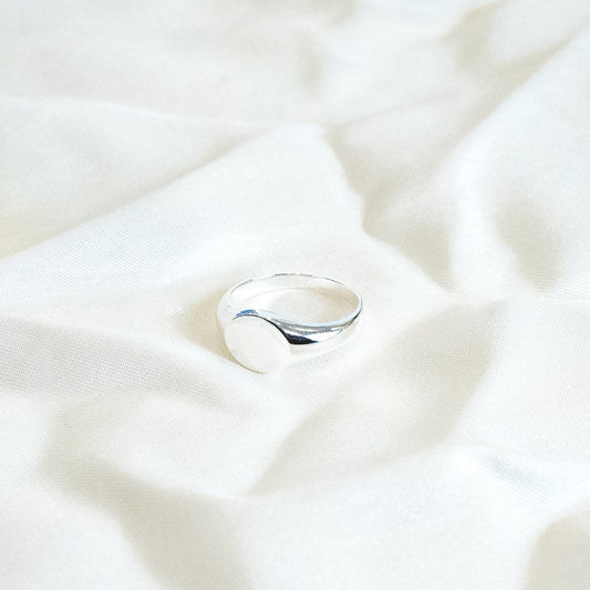 The ring forms a simple, circular shape that elegantly wraps around the finger. The sterling silver band is coated in a warm, golden layer of vermeil, giving it a timeless look reminiscent of classic Roman medallion designs.