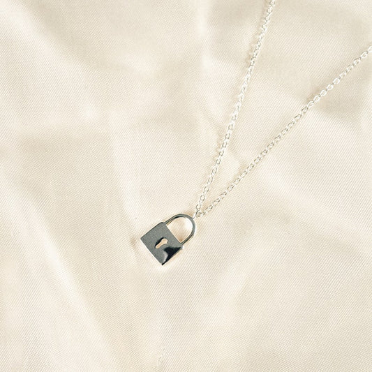 The necklace is a silver chain with a small padlock pendant. The padlock is rectangular and has a curved shackle. The  pendant is  silver and shiny.