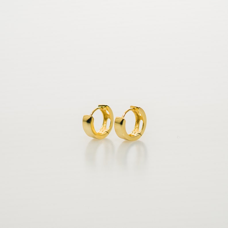 Round hoop earrings in gold vermeil on sterling silver, 10mm diameter, 1-3mm thick. Hinged closure for secure fit. Smooth, polished finish. Lightweight and comfortable for cartilage, daith, rook or helix piercings.