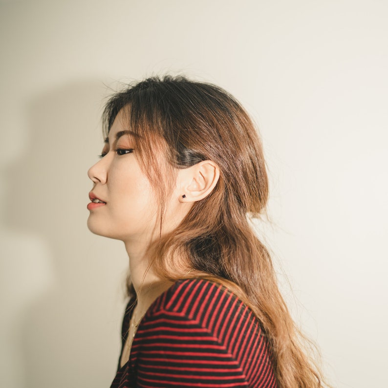 These earrings feature small, square-cut gemston in obsidian, set in sleek sterling silver studs. The minimalist design complements various ear piercings, from cartilage to lobes.