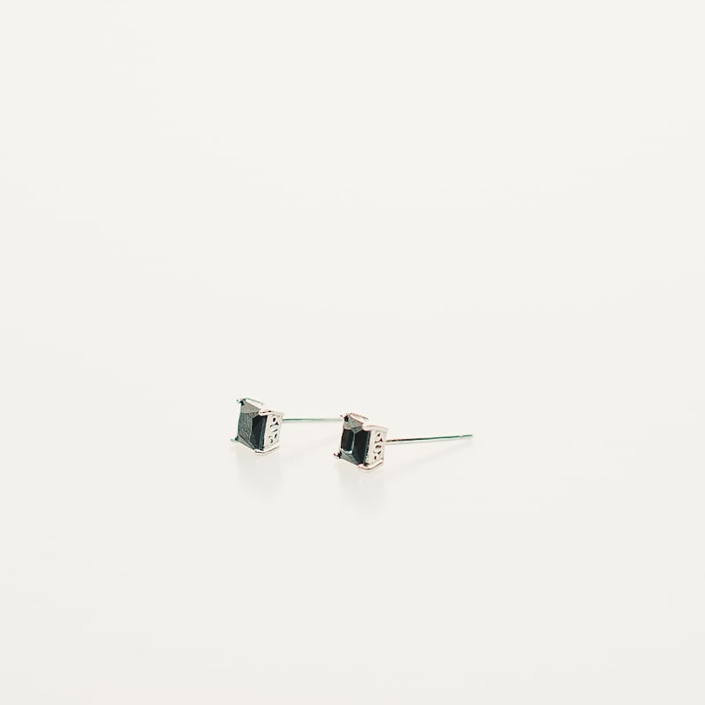 These earrings feature small, square-cut gemston in obsidian, set in sleek sterling silver studs. The minimalist design complements various ear piercings, from cartilage to lobes.