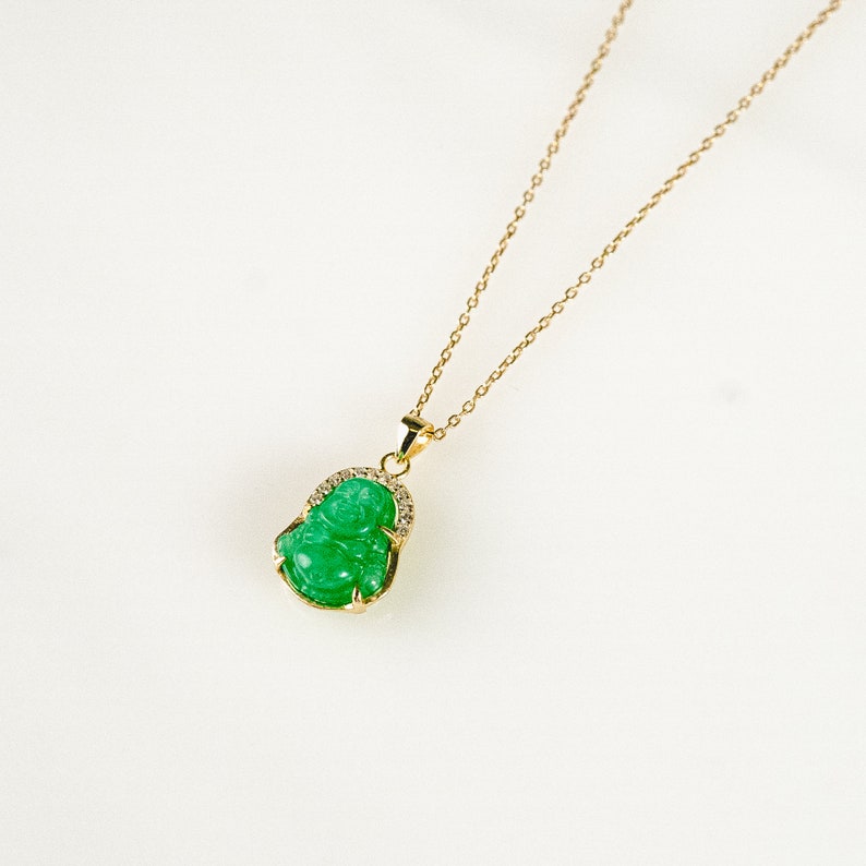 Pendant necklace featuring a small, 3D carved jade Buddha charm. Vibrant green jade stone set in 18k gold vermeil. Thin, adjustable gold vermeil cable chain, 16-18&quot; long with lobster clasp closure. Delicate and lightweight.