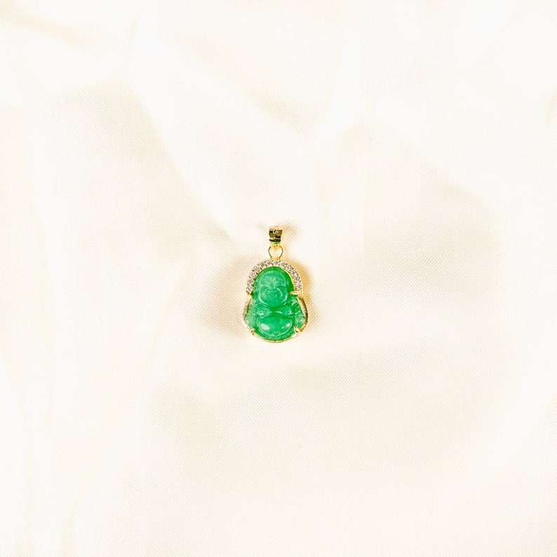 Pendant necklace featuring a small, 3D carved jade Buddha charm. Vibrant green jade stone set in 18k gold vermeil. Thin, adjustable gold vermeil cable chain, 16-18&quot; long with lobster clasp closure. Delicate and lightweight.